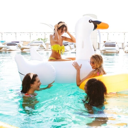 Group of women in a swimming pool with inflatable toys enjoying a girlfriends getaway together.