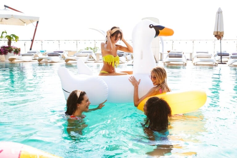 Group of women in a swimming pool with inflatable toys enjoying a girlfriends getaway together.