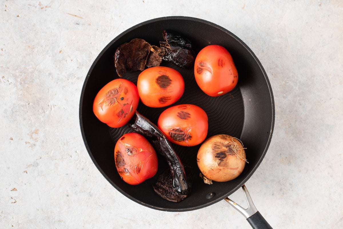 Chile guaque, chile pasa and Roma tomatoes in a skillet.