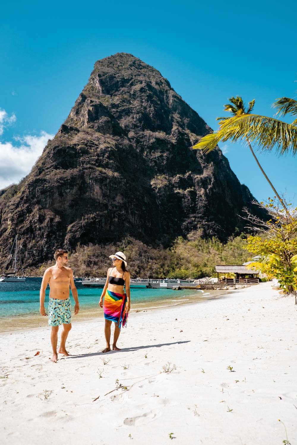 Couple walking on a beach in St. Lucia holding hands on a Caribbean honeymoon. 