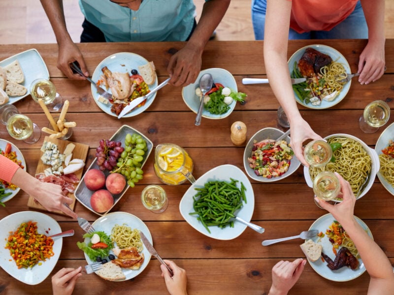 Group of people eating food at a wooden table.