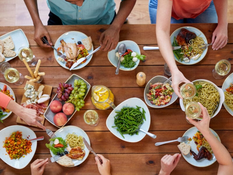 Group of people eating food at a wooden table.