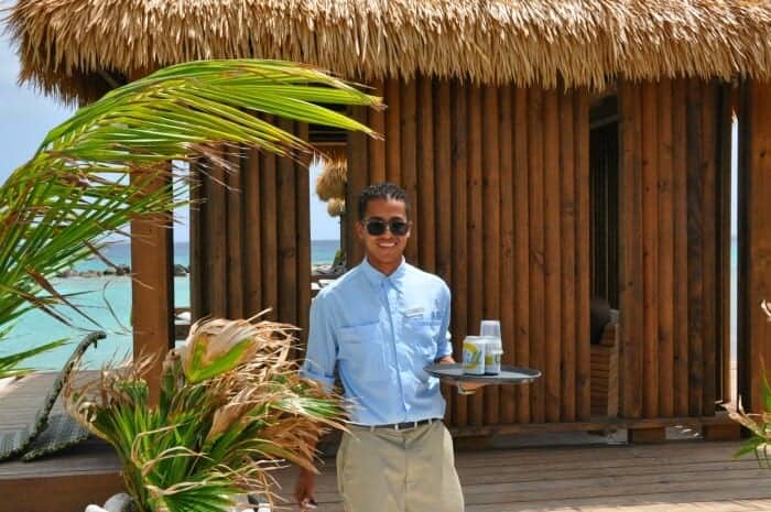 Server with a beer on a tray at a private cabana at Flamingo Beach on Renaissance Island Aruba.