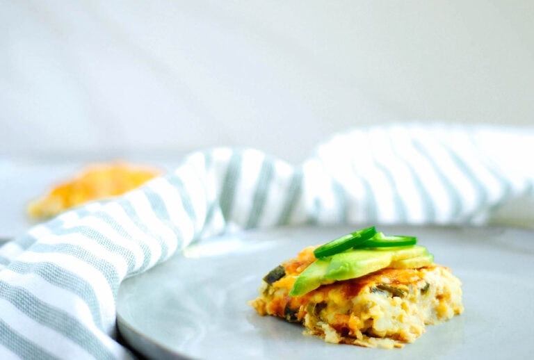 A meatless egg bake topped with avocado, served on a white plate.