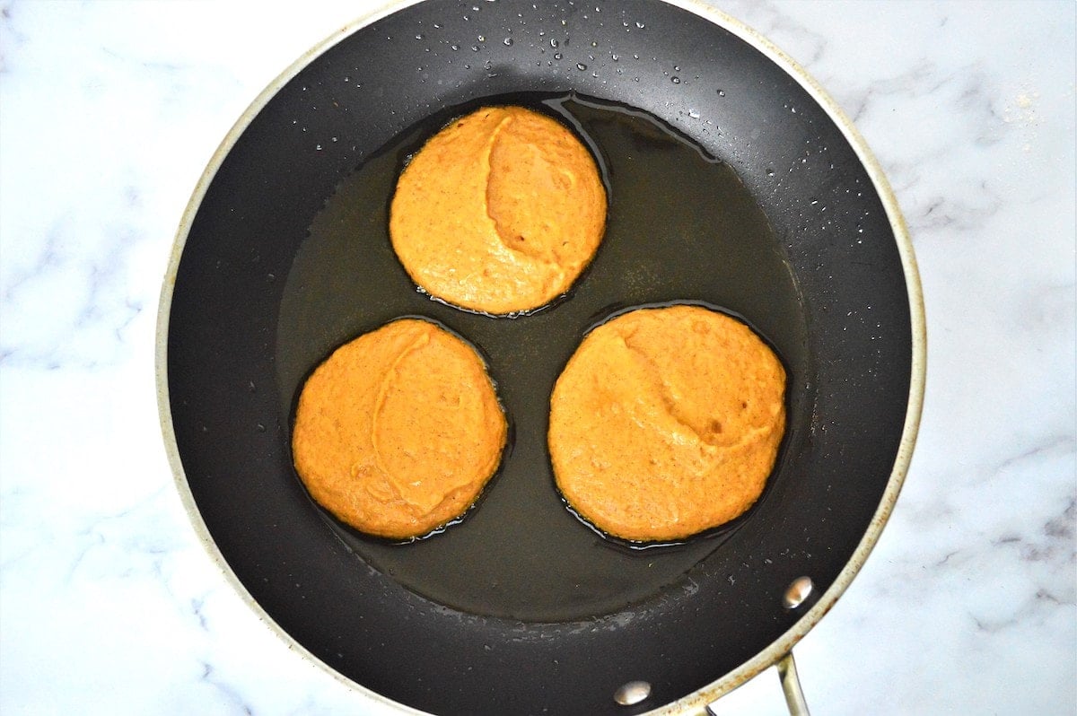 Process shot of pumpkin pancakes in skillet.
