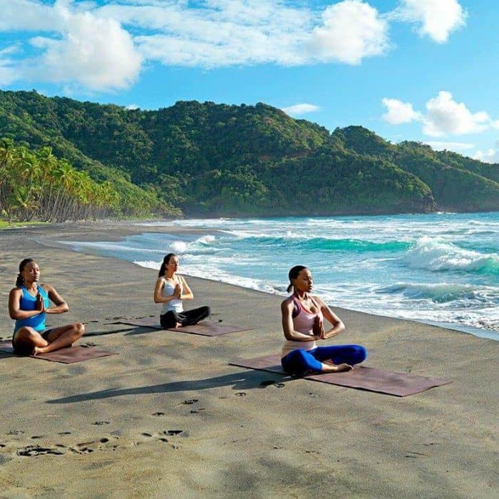 Women doing yoga on the beach during a girls getaway on at Rosalie Bay Resort Dominica
