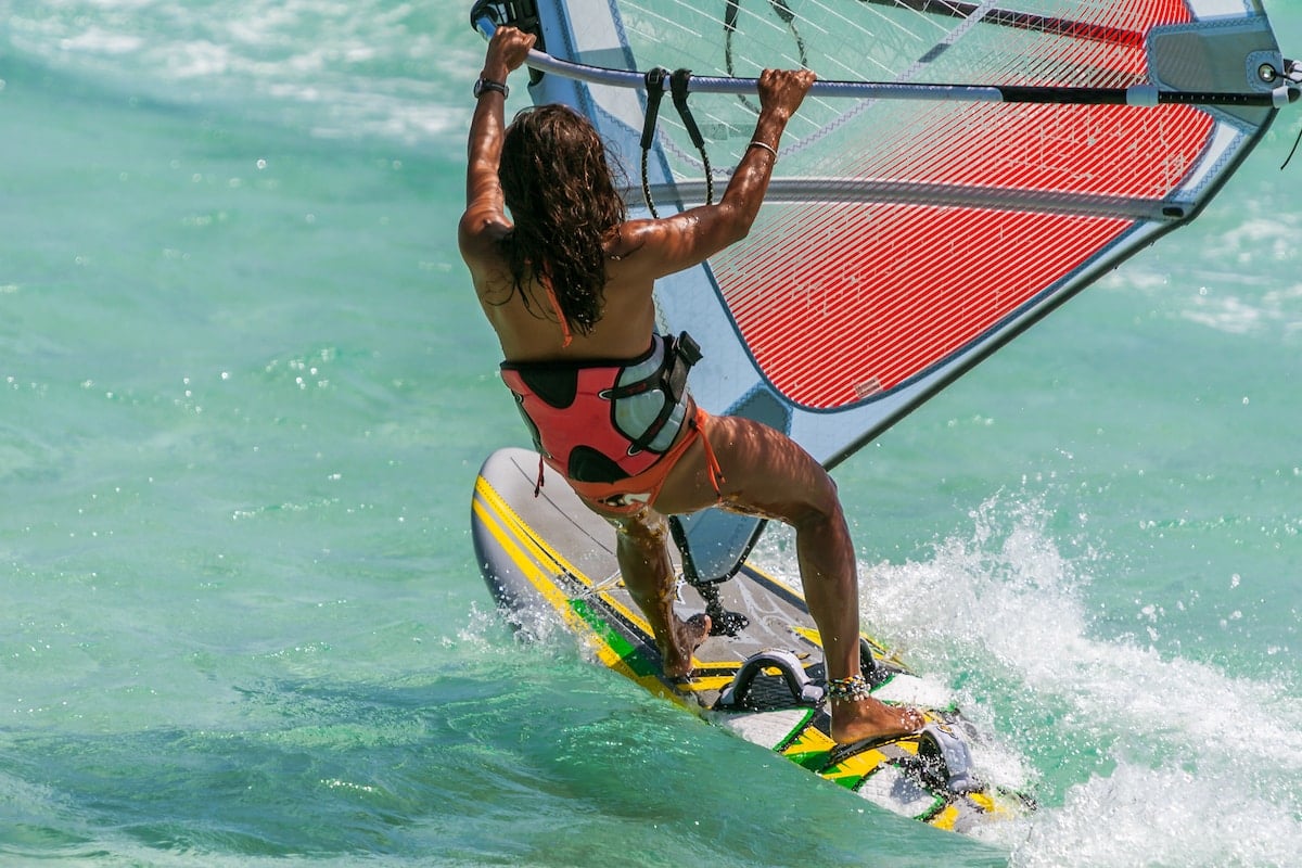 Woman windsurfing in clear blue waters.