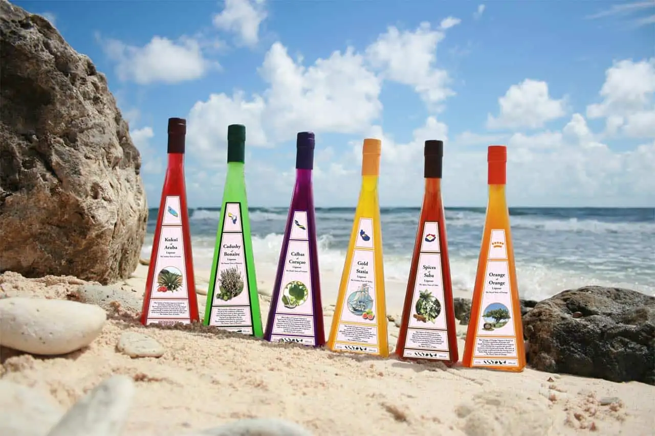 Bottles of Cadusht Liqueurs set on an ocean shore. 