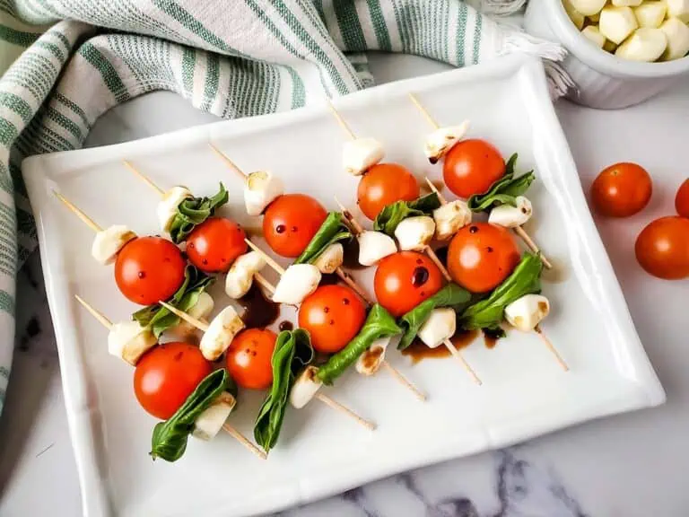 Caprese salad skewers on a platter with balsamic vinegar over the top.