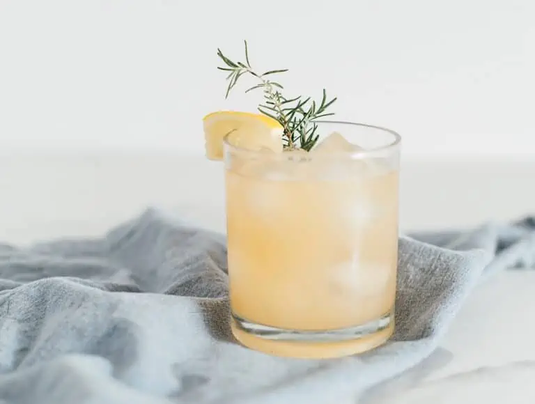 A chamomile whiskey cocktail in an old-fashioned glass on a blue napkin.