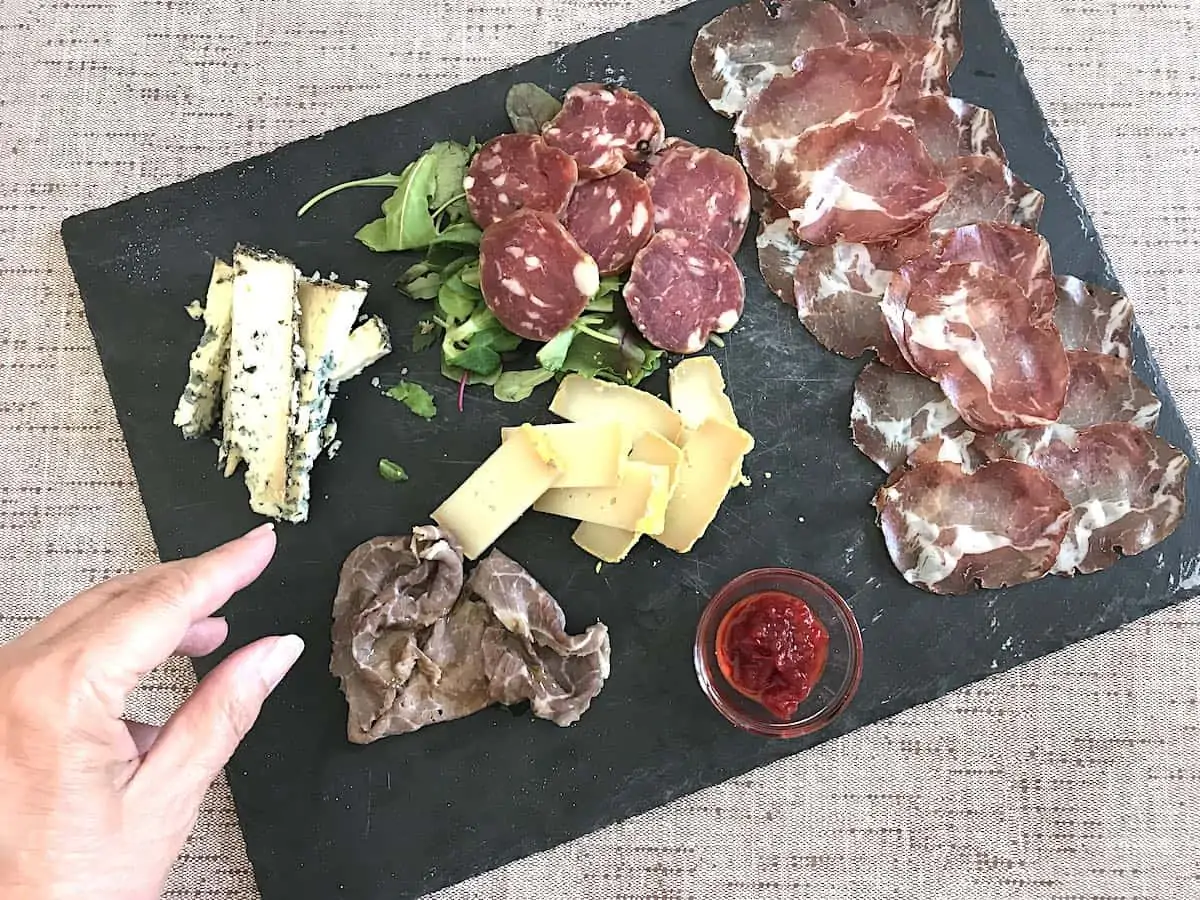 Woman reaching for food on a charcuterie tray in Italy.