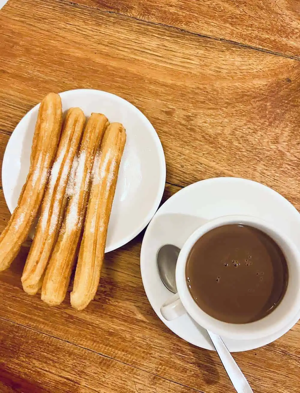 A mug of hot chocolate with four nd churros in Barcelona.