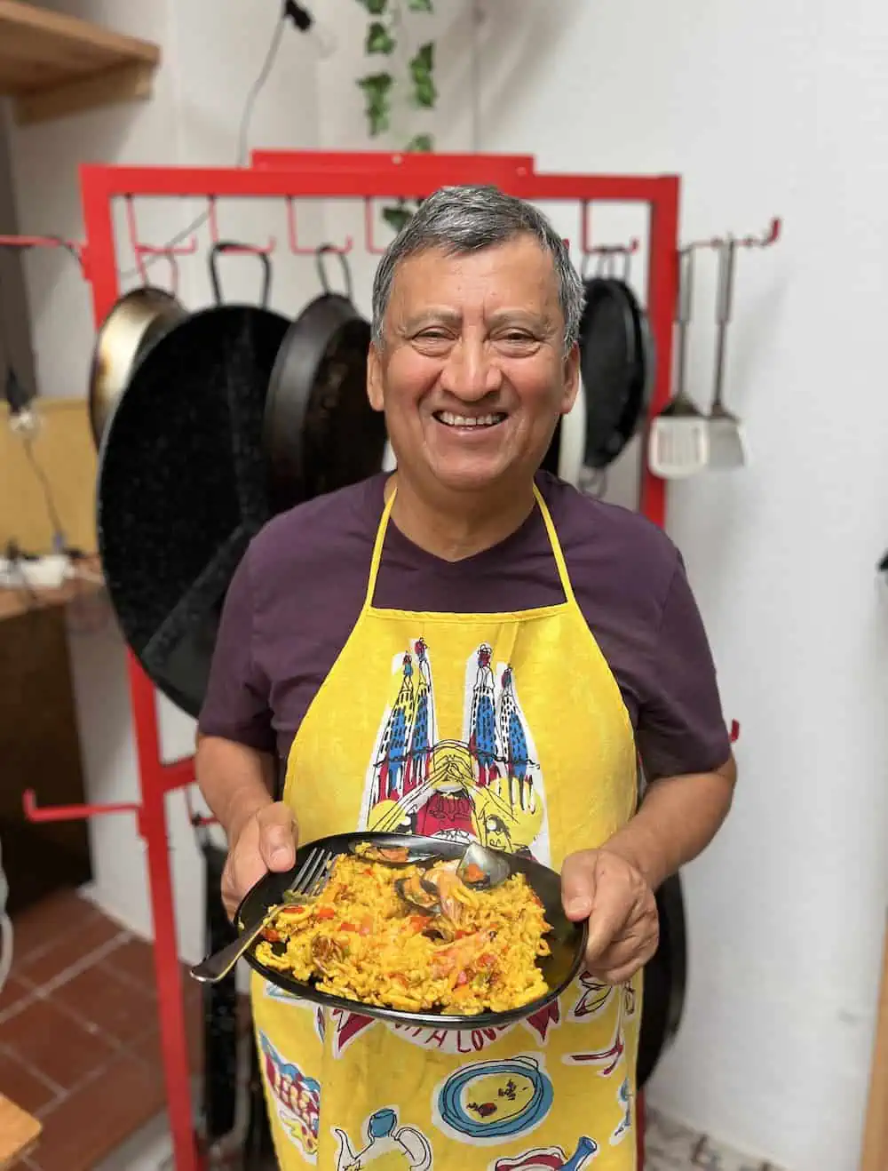 Francisco Sanchez of A Taste for Travel holding a plate of paella in Barcelona. 