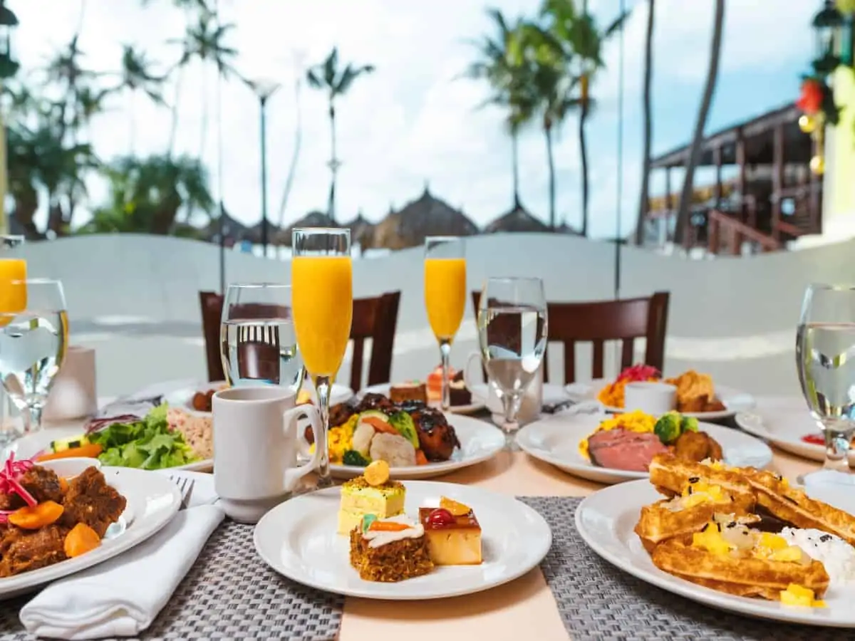 Plates of breakfast food and drinks on a table near the ocean