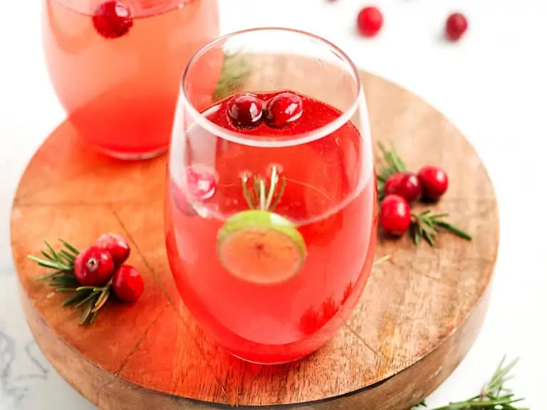 Two glasses of cranberry prosecco cocktail on a wooden board for Christmas.