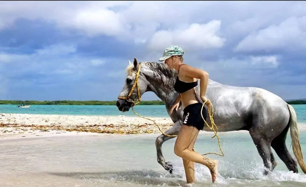 Woman and a horse beside the sea horseback riding in Bonaire, Dutch Caribbean. 