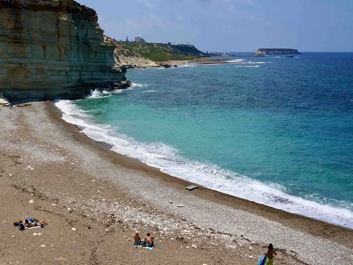 People sunbathing beneath a cliff at White River Beach near Paphos Cyprus.