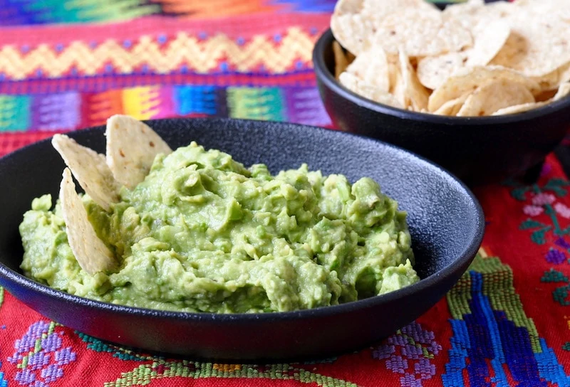 Guatemalan Guacamole in an earthen bowl on a Mayan weaving.