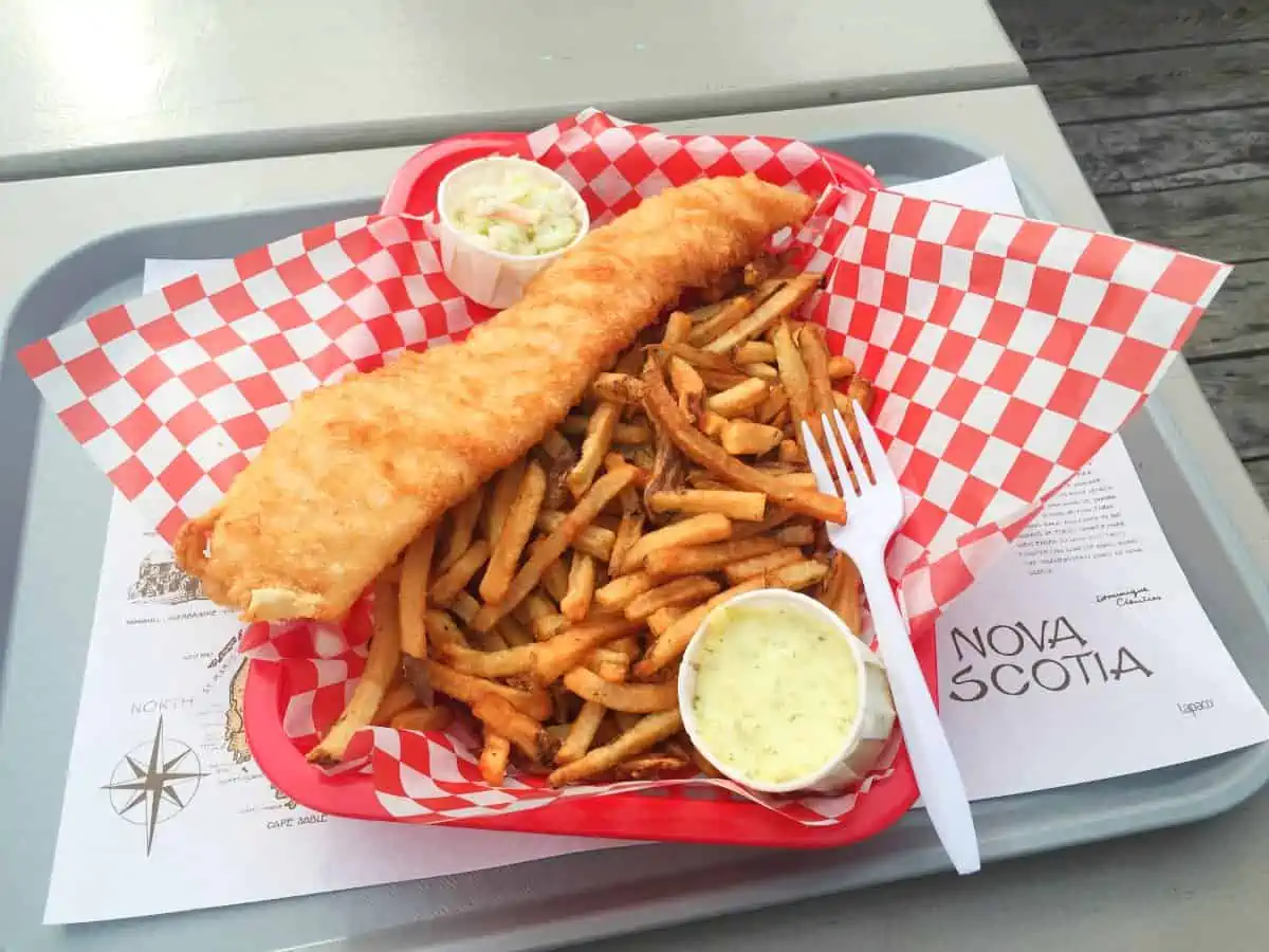 Deep fried Fish and chips in basket with plastic fork. 