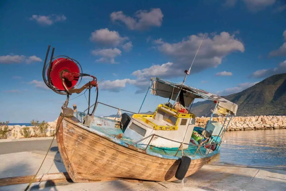 Abandoned wooden fishing boat against a dramatic blue sky in the port of the sea-side village of Pomos, island of Cyprus.