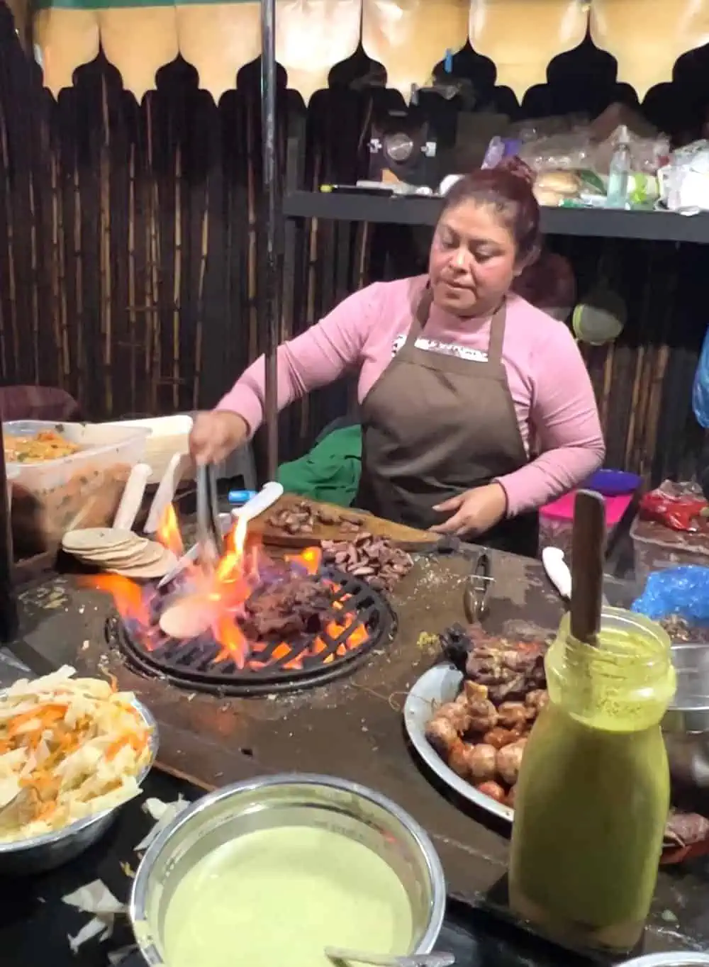 Woman grilling meat for mixtas on a grill. 