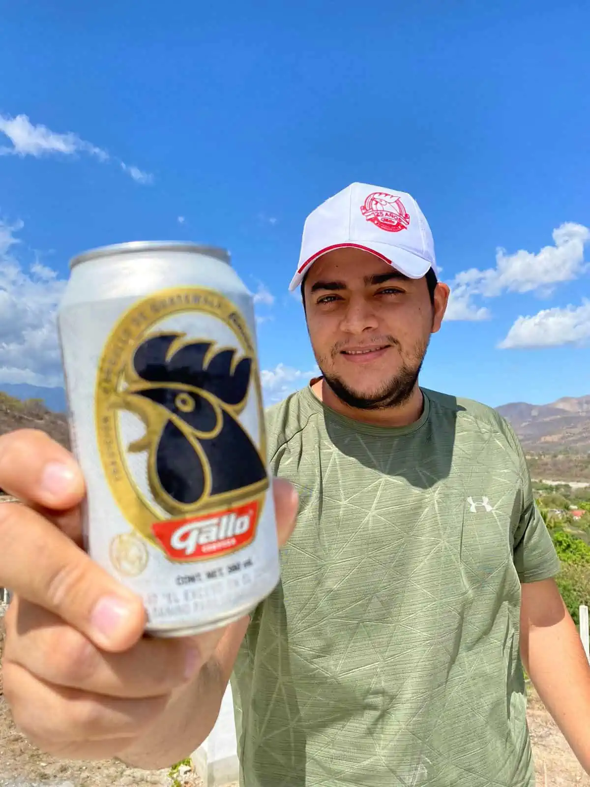 Guatemalan man holding a Gallo beer in the countryside. 