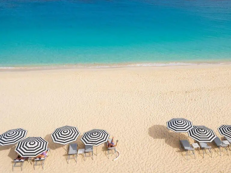 Overhead view of a beach in Anguilla with umbrellas on the sand.