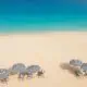 Overhead view of a beach in Anguilla with umbrellas on the sand.