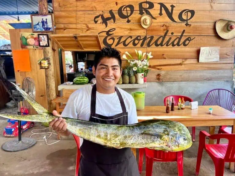 Young man holding a dorado fish in a Puerto Escondido restaurant.