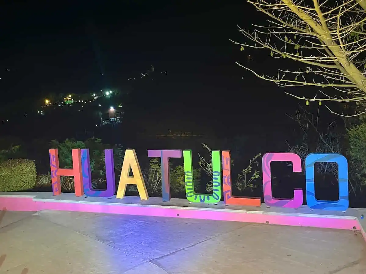 The HUATULCO sign illuminated at night. 