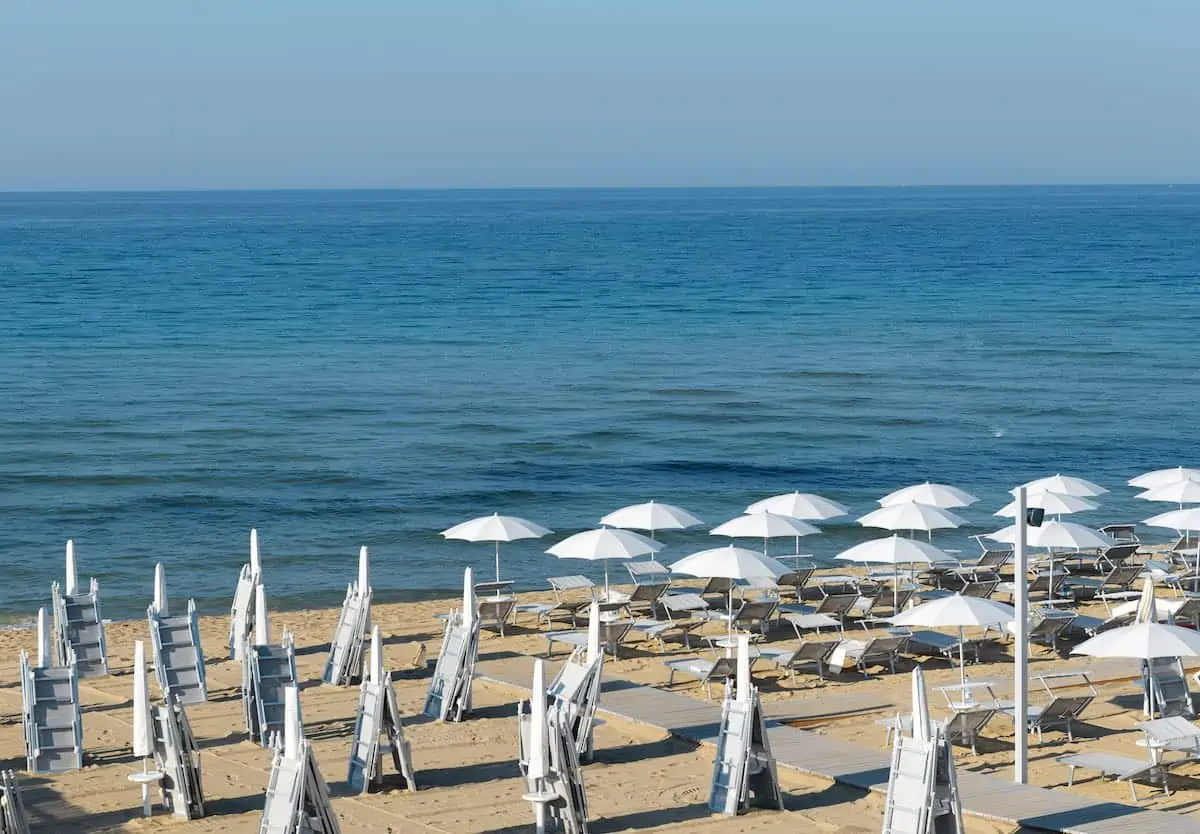 In the morning umbrellas on the beach of Lido di San Pietro in region of Puglia with Ionian Sea in the background.