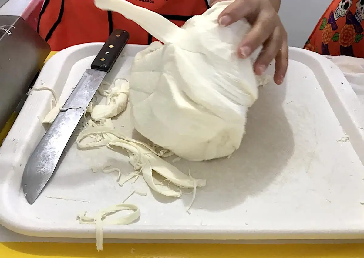 A ball of Oaxacan cheese being unfurled like string.