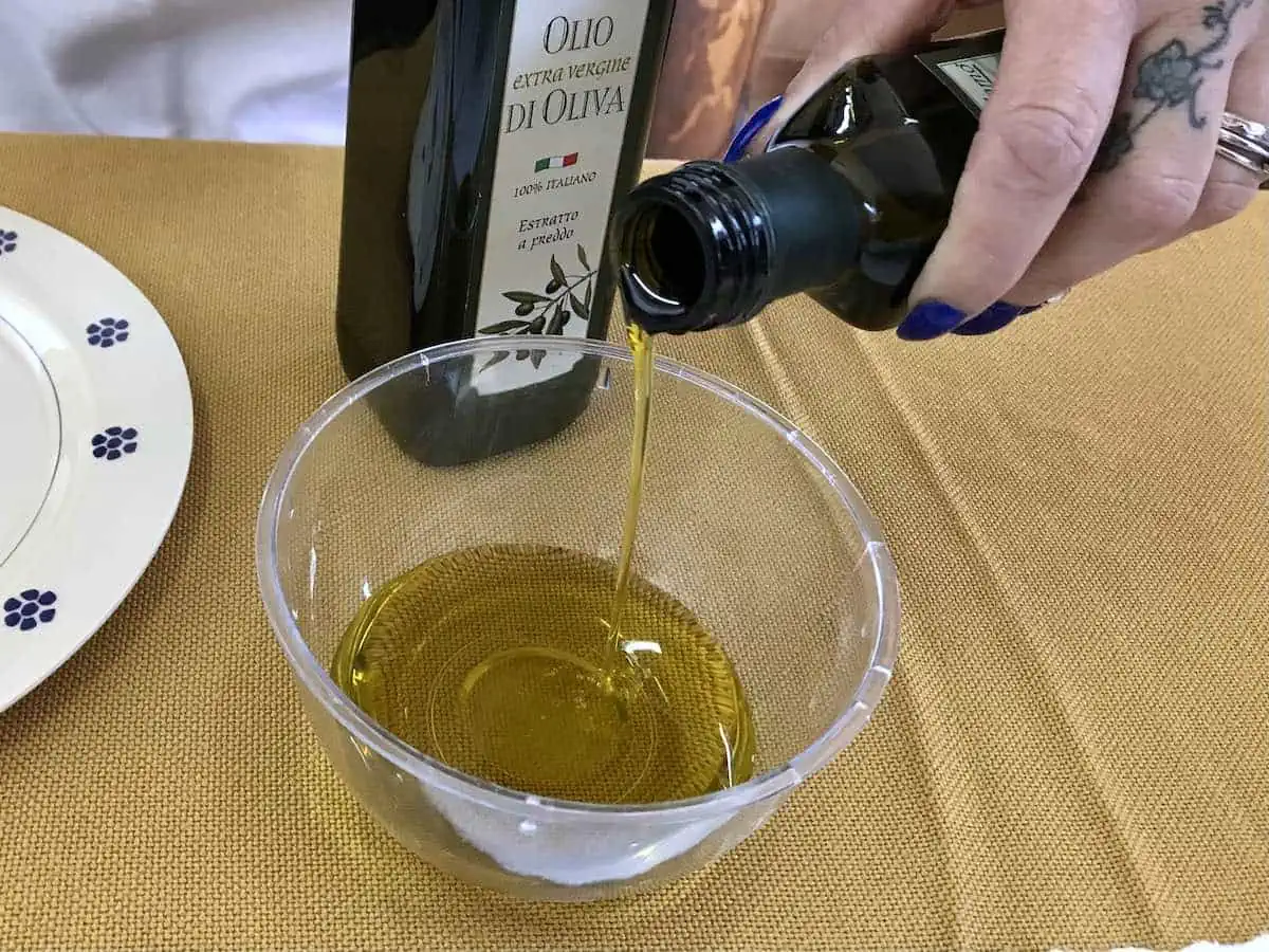 A woman pouring Italian olive oil into a cup. 