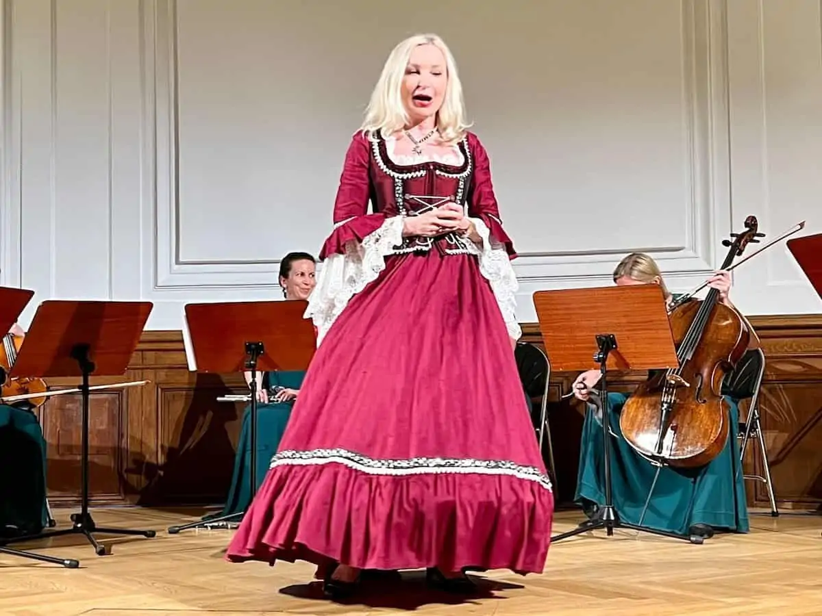 A female opera singer in a red dress on stage. 