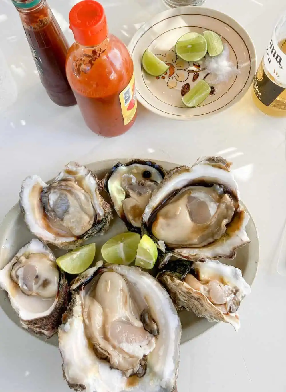 A platter of six fresh oysters with hot sauce.  