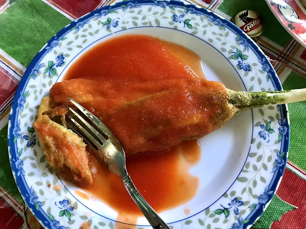 Guatemalan pacaya in salsa with a fork on a blue plate.