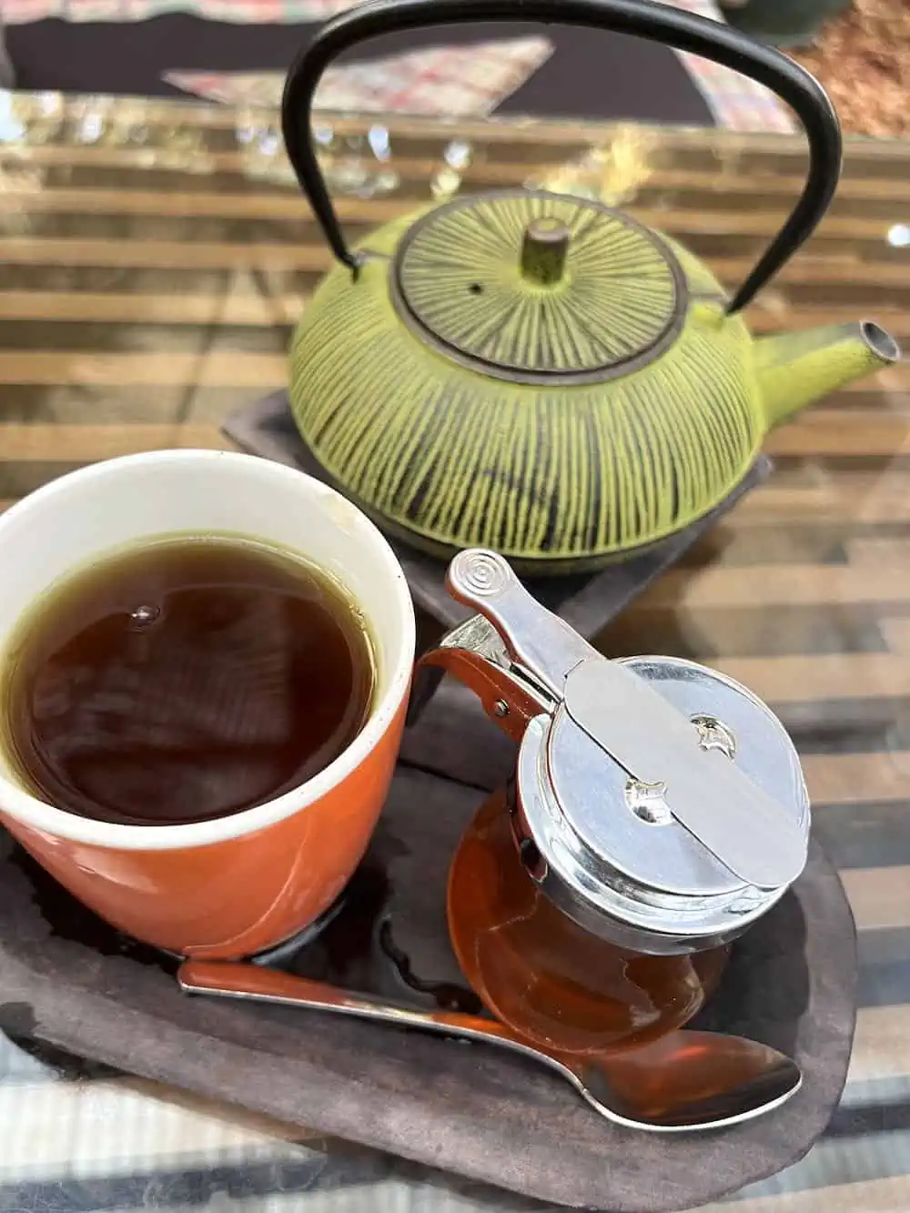A mug of Pericón tea, a herbal infusion, with a teapot and honey. 