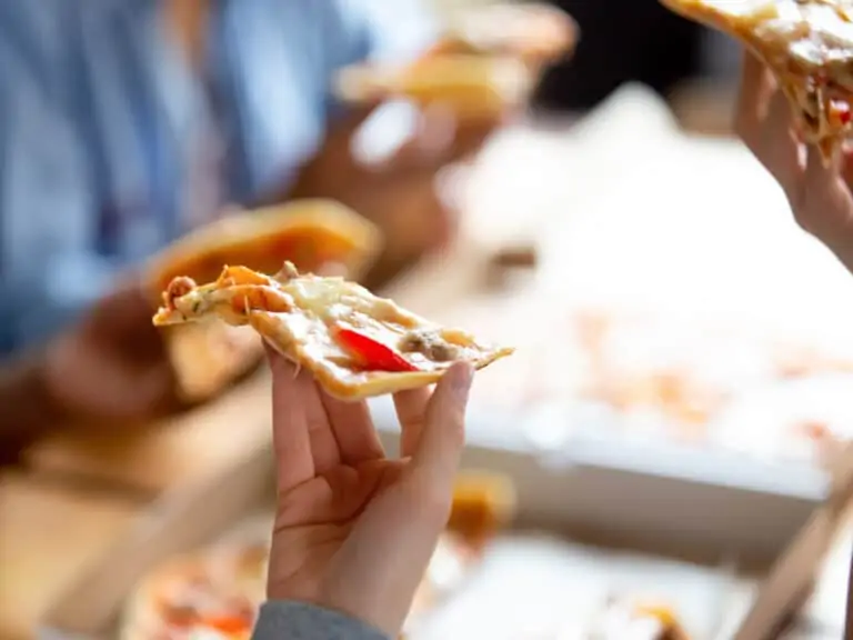 Person eating pizza on the street.