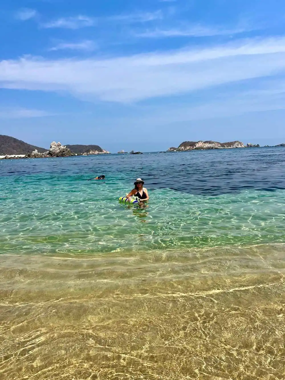 A person snorkeling and another person standing in clear water at Playa San Agustin, Huatulco)