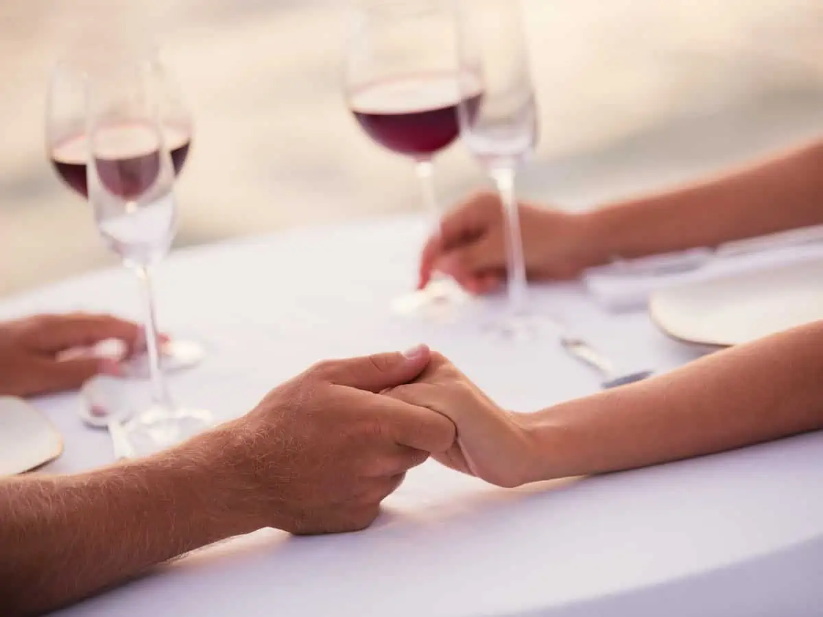 A couple holding hands while dining on the beach.