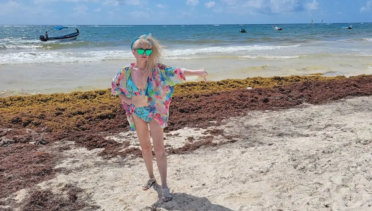 Woman standing in front of Tulum seaweed in 2022. 
