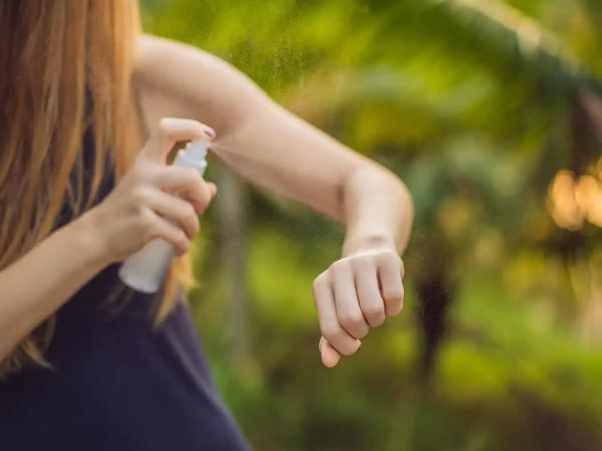 Close-up of a woman spraying insect repellent on her arms. 