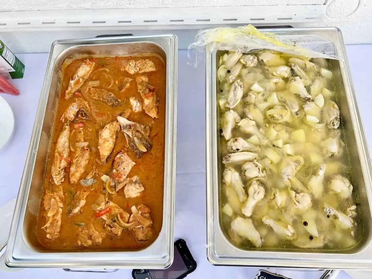 Stew fish and chicken souse in pans on table. 