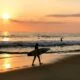 Surfer with board on a beach at sunset in Puerto Escondido, Oaxaca, Mexico.