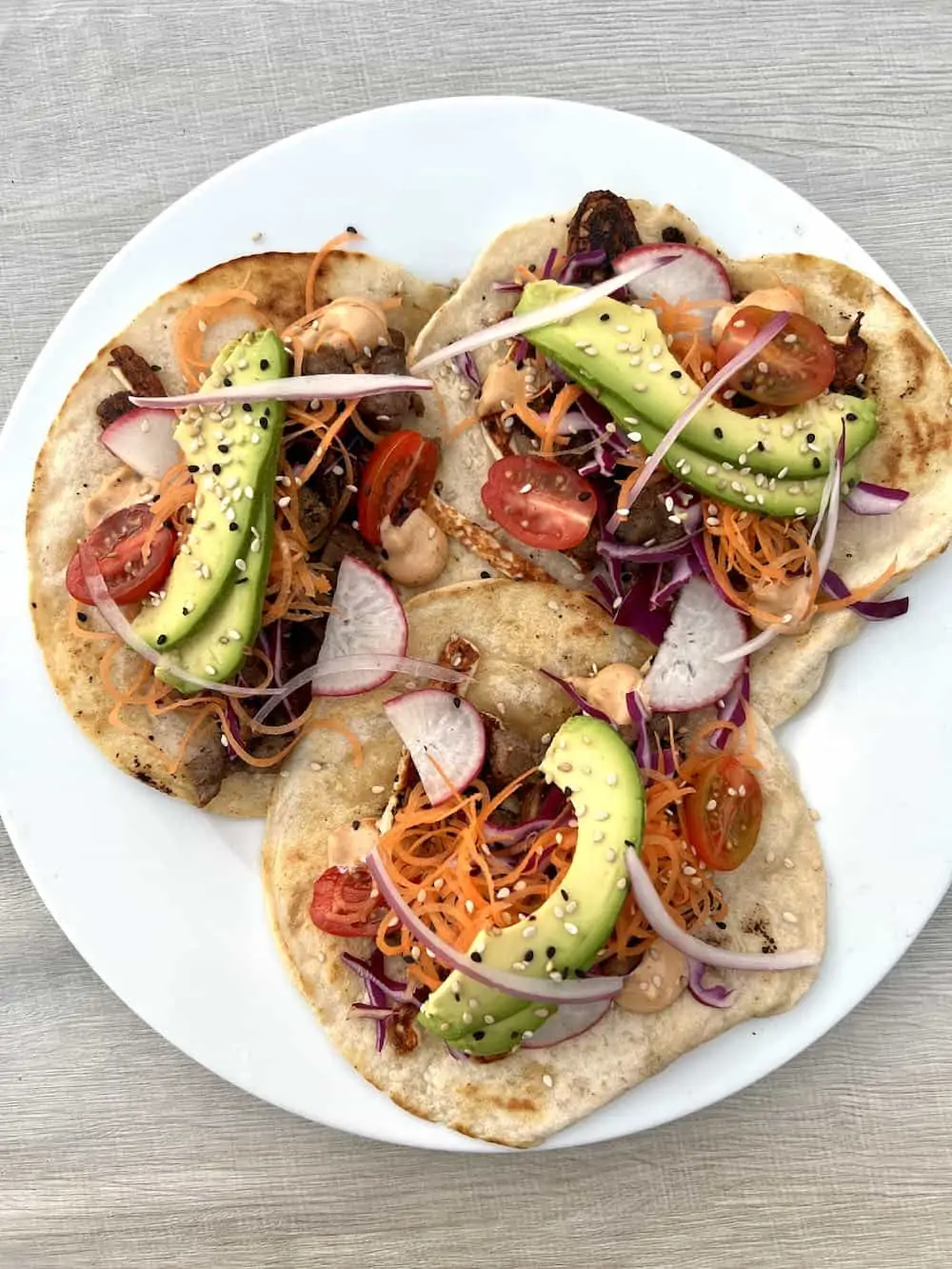 Three beef tacos on a white plate at Escondido Brunch and Seafood restaurant in Puerto Escondido Oaxaca Mexico.