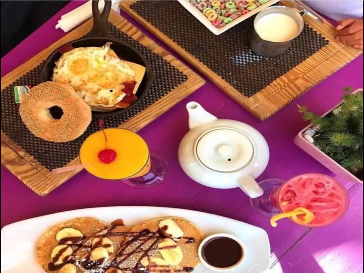 Bagels and pancakes on plates with a tea pot on a table