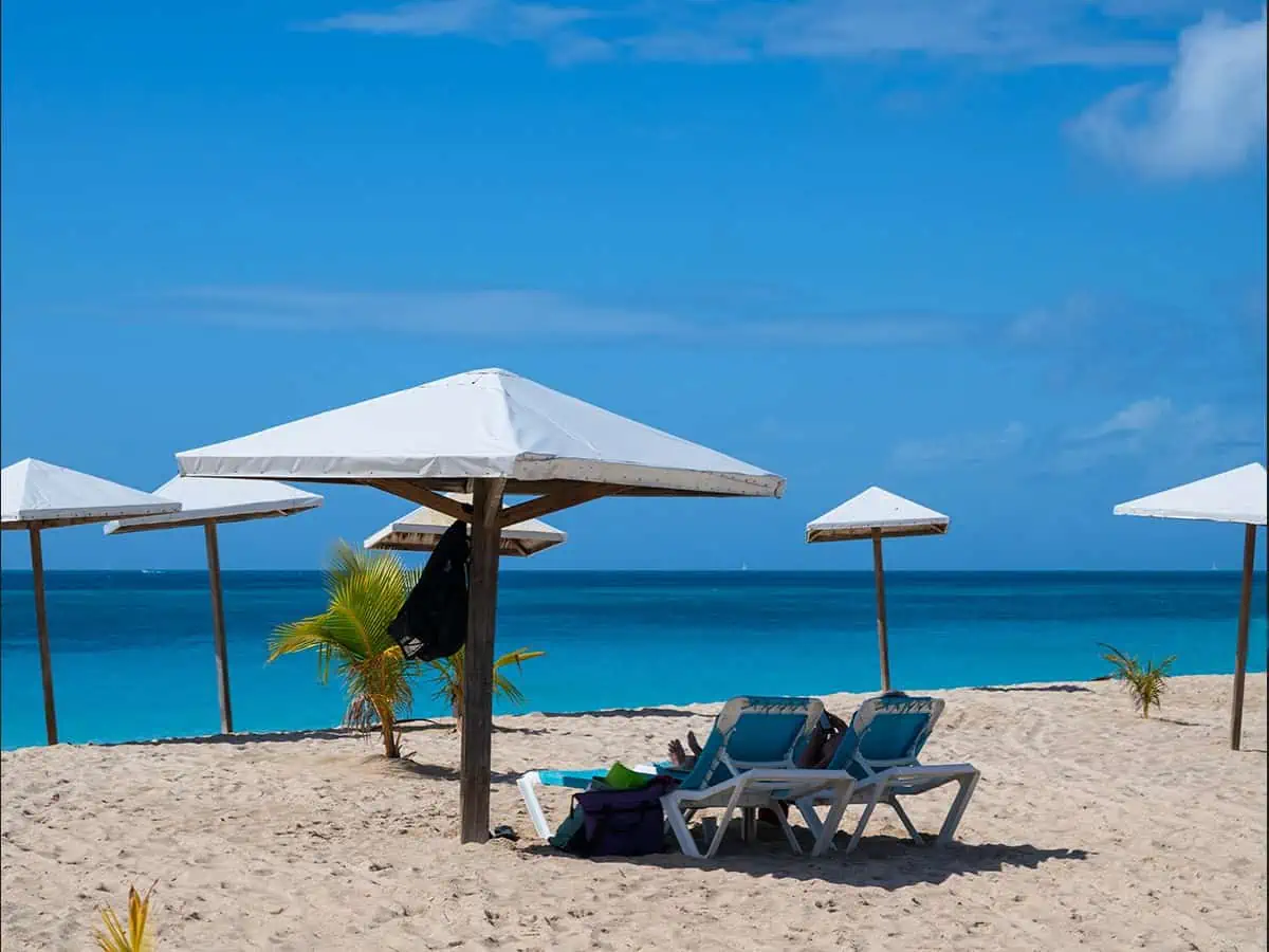 Beach lounge chairs on beach with umbrellas at Turners Beach Antigua.