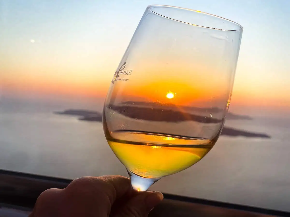Person holding a wine glass during a santorini sunset wine tour.