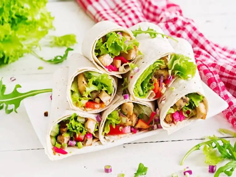 A stack of wrap sandwiches with a red gingham napkin.