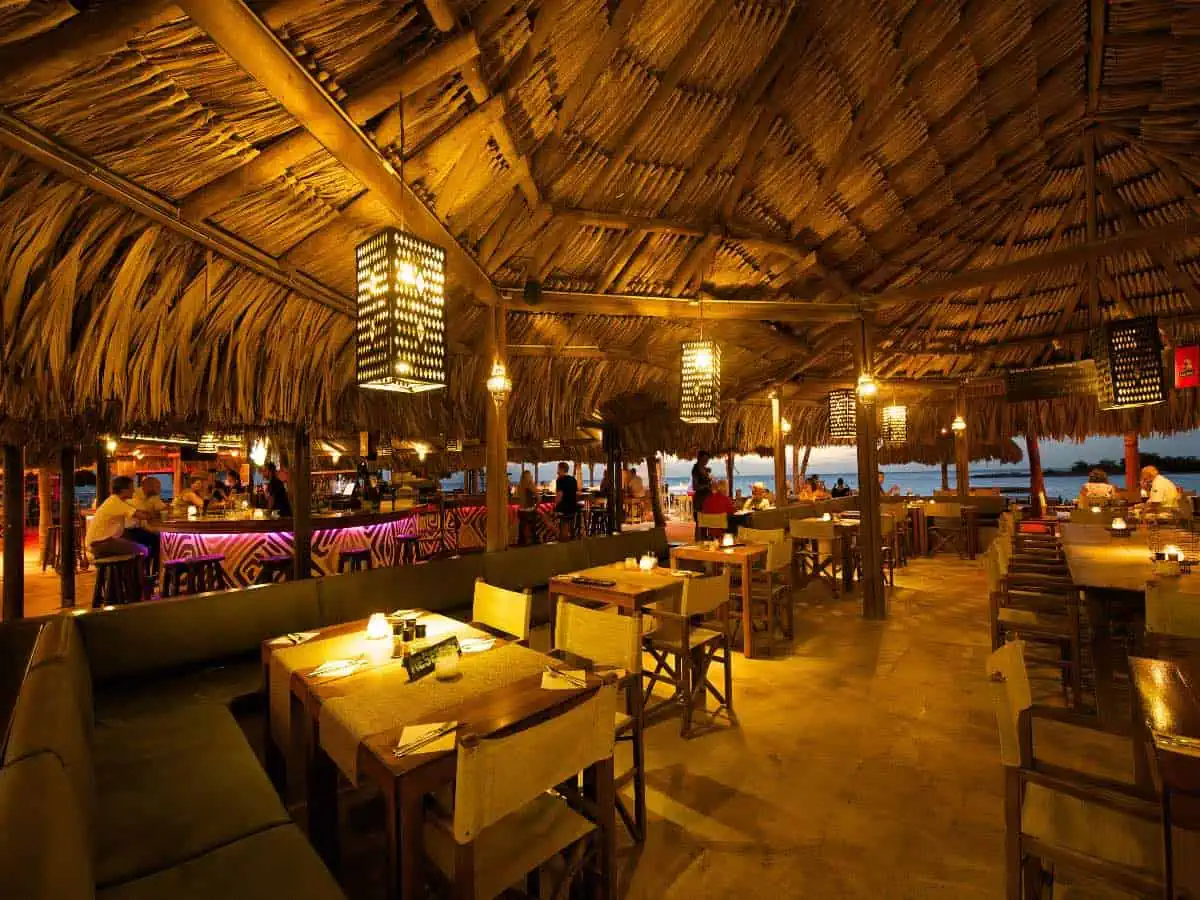 Restaurant tables under tiki hut in the evening.